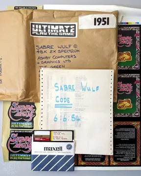 An Ultimate envelope addressed to Ashby Computers and Graphics, with a fan-fold printout marked Sabre Wulf code 6:6:84, a Maxell floppy disk labelled Sabre Wulf 6th June 1984, logo stickers and an uncut sheet of inlay prints